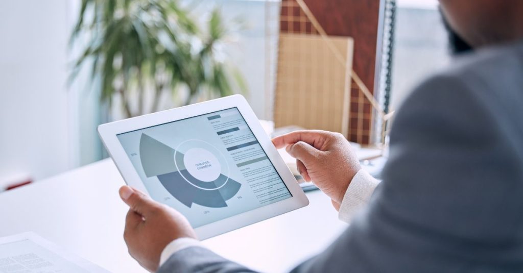 Male CFO in office using tablet with cashflow graph view in dashboard of cloud ERP software, working on expense management